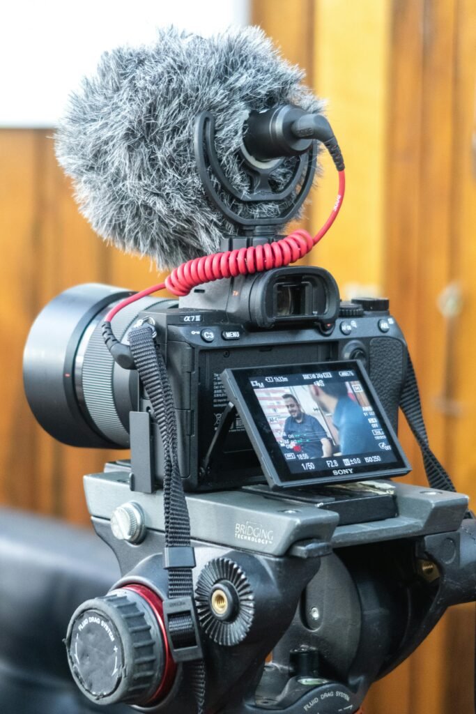 Close-up of video camera with microphone setup indoors for filming.